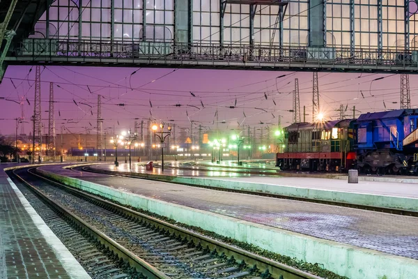 Train with industrial equipment at the railway station at night.