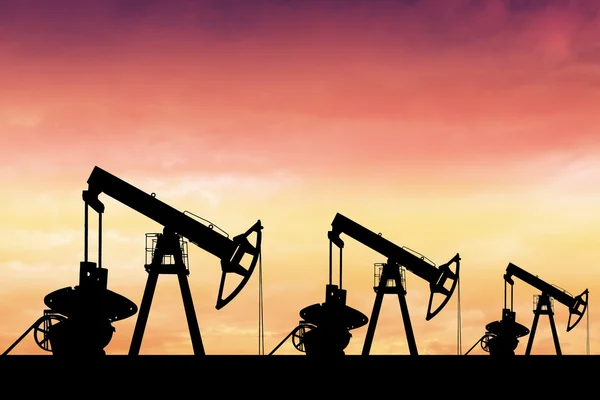 Silhouette of three oil pumps at sunset.