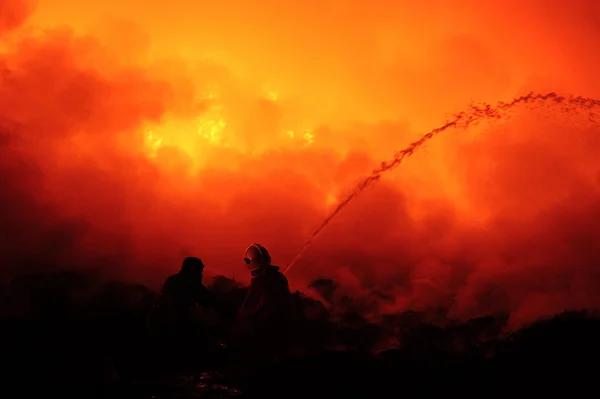 Silhouette of fireman fighting bushfire at night.