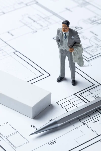 Real estate businessman miniature with eraser and pencil on architect blueprint for concept of housing market
