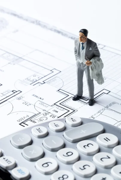 Entrepreneur miniature with calculator on architect blueprint for housing cost and design