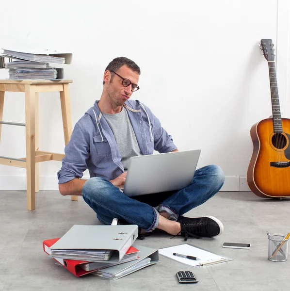 Creative start-up entrepreneur working budget sitting on floor with laptop at home-office