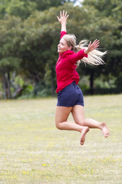 Thrilled young woman jumping high with happiness in sunny park