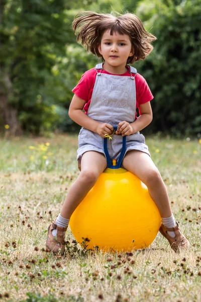 Smiling young kid jumping and bouncing on a hopper ball