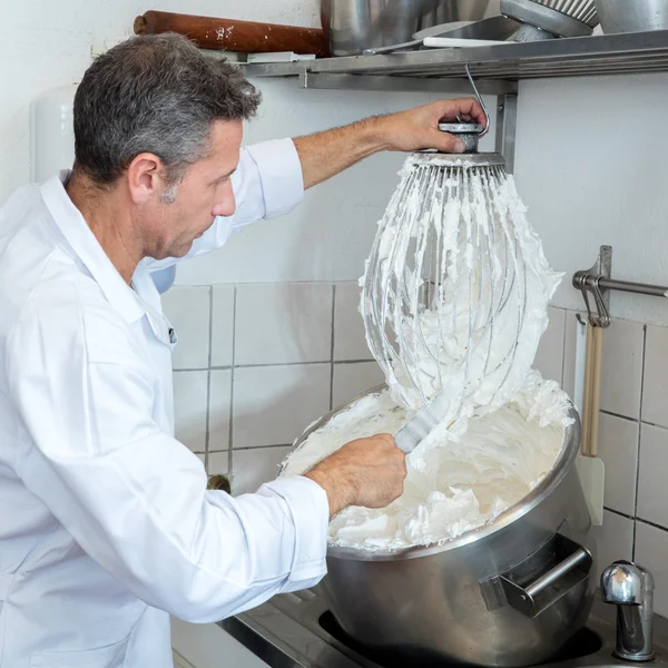 Male professional cook cleaning big whisk to prepare French specialty