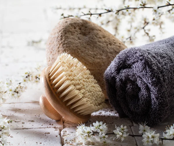 Body brush and stone over fresh flowers for beauty