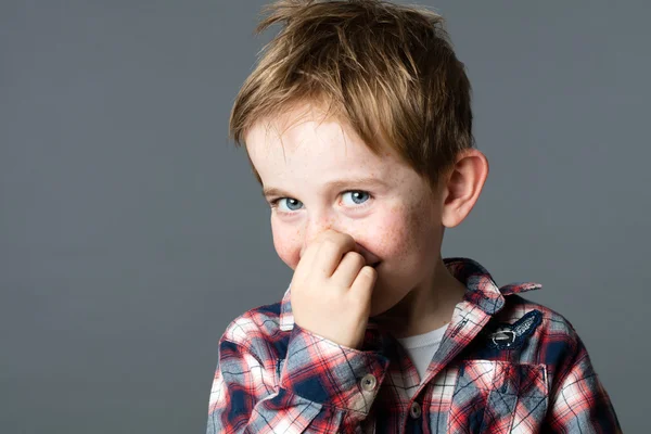 Cute little boy picking his nose to act mischievous