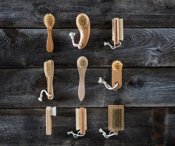 Collection of body brushes on old wood background, top view