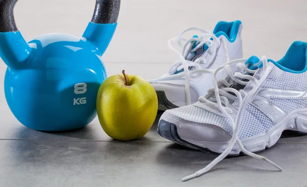 Toning up exercise concept with sneakers, kettle bell and apple