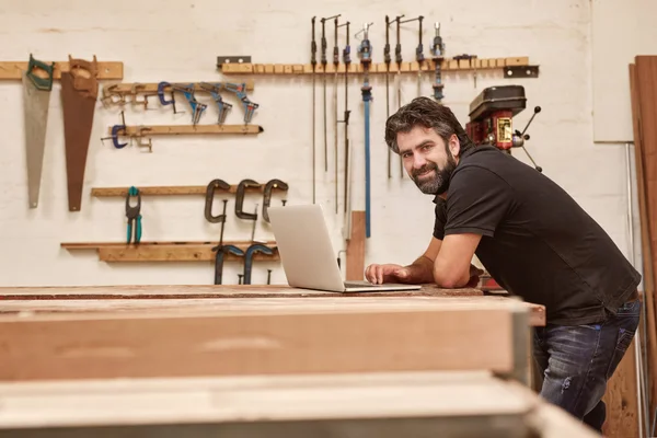 Designer working on laptop on workbench in studio