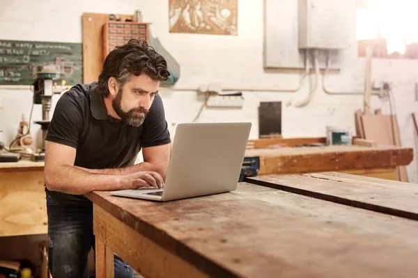 Designer working on laptop on workbench in studio