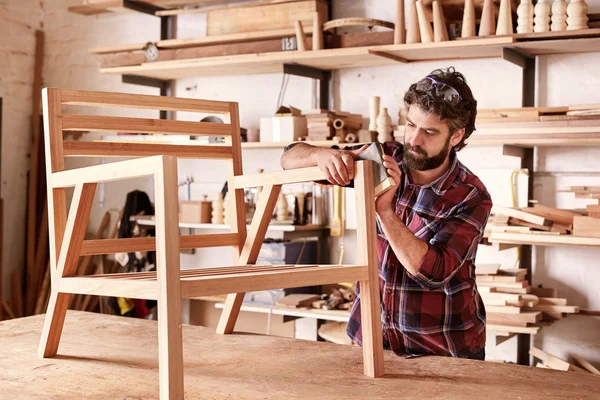 Artisan carefully sanding chair frame