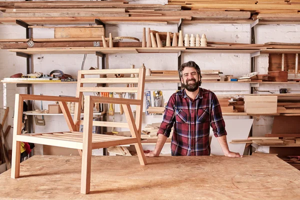 Craftsman in woodwork studio with wooden chair