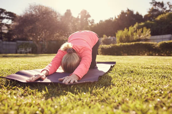 Woman in yoga pose on mat outdoors