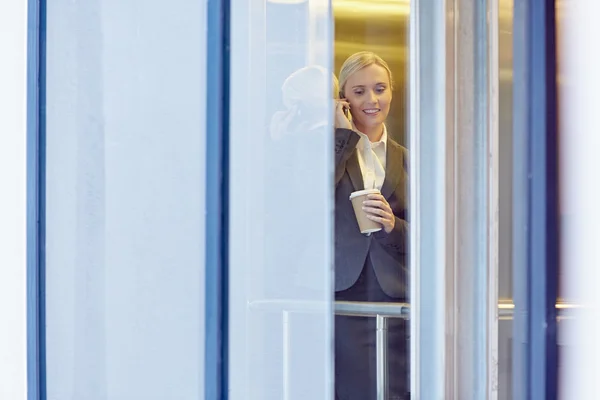 Businesswoman talking on phone in elevator