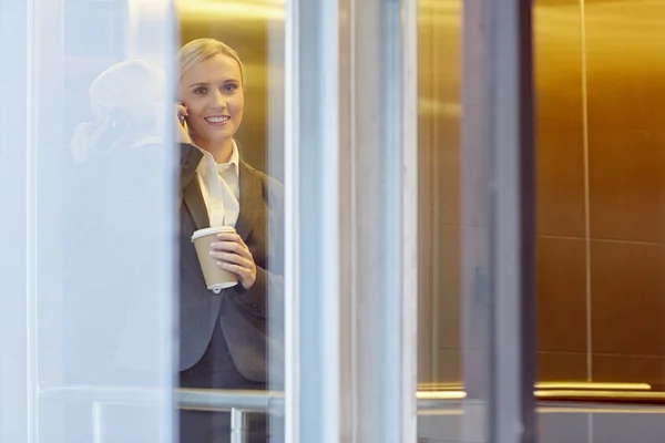 Businesswoman talking on phone in elevator