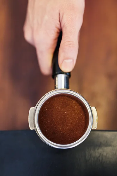 Hand holding portafilter with ground coffee
