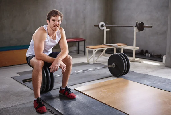 Man sitting on wieghts looking at camera