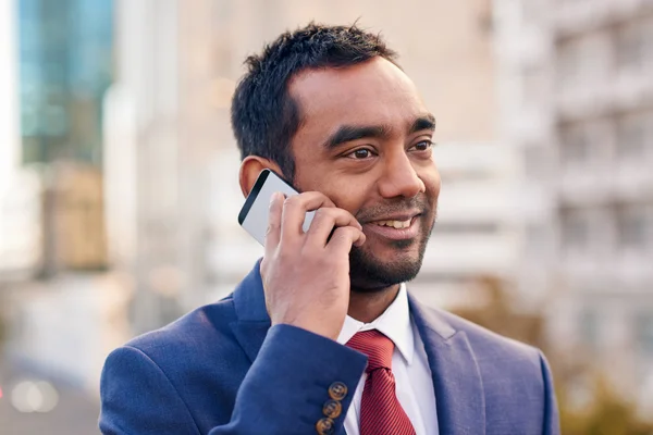 Businessman talking on cellphone while standing in city