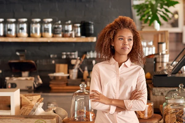 Woman standing with arms crossed in cafe