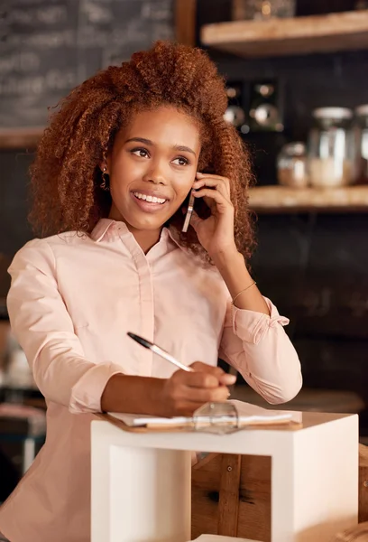 Woman talking on phone while working in cafe