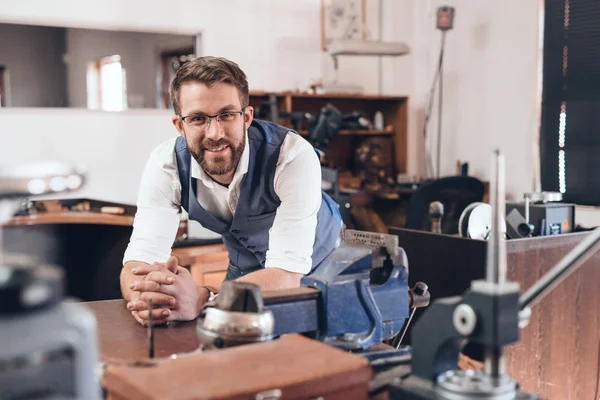 Jeweler leaning on bench in workshop full of tools