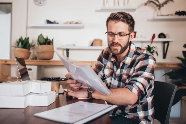 Entrepreneur using laptop and reading paperwork