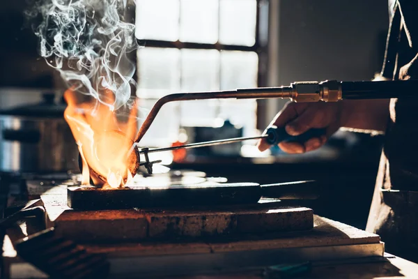 Jeweler using torch to melt metal