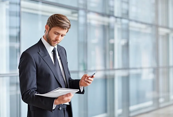 Businessman holding cell phone and documents