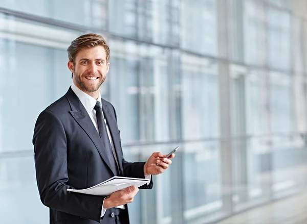 Businessman smiling and holding phone and notes