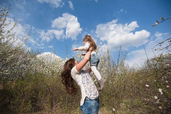 Mom throws daughter plays on the background of blue sky in spring