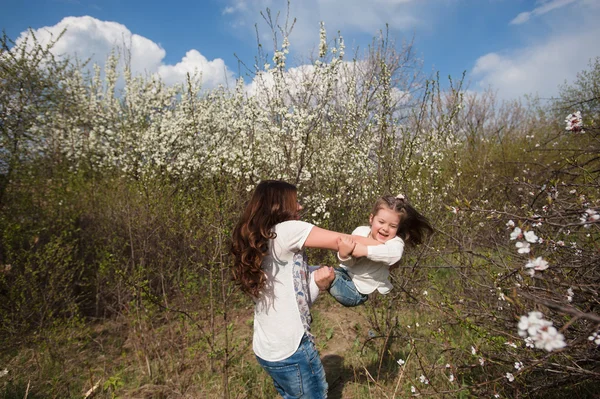 Mom throws daughter plays on the background of blue sky in spring