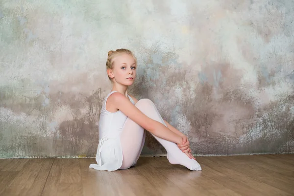 Little ballet dancer sitting white swimsuit, dance, sports, healthy lifestyle, ballet