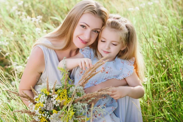 Mom and daughter in nature with a bouquet of wild flowers