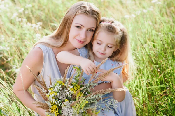 Mom and daughter in nature with a bouquet of wild flowers