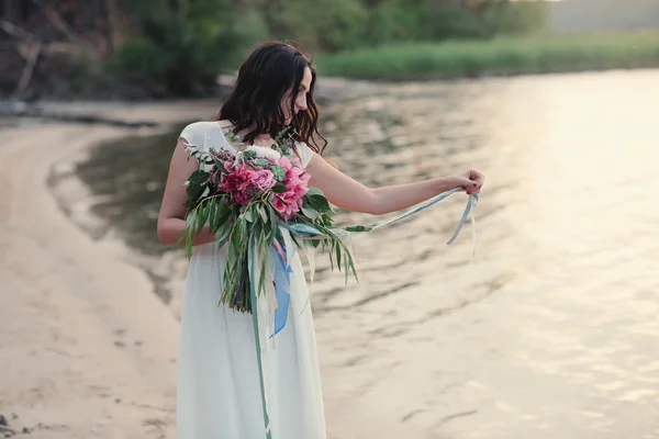 Beautiful girl with a bouquet of flowers is a bouquet on the beach