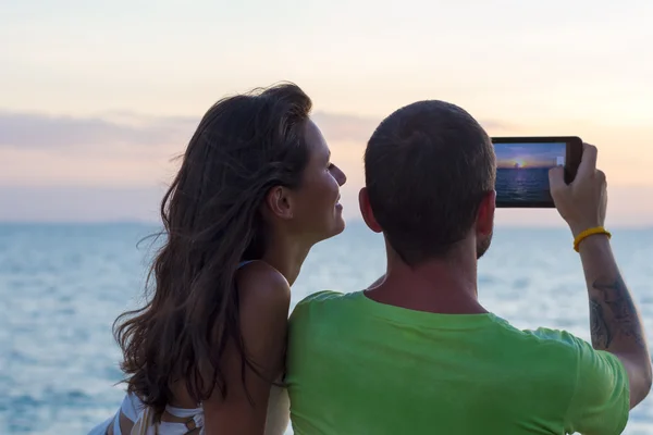 Young mixed couple are photographed on the tablet