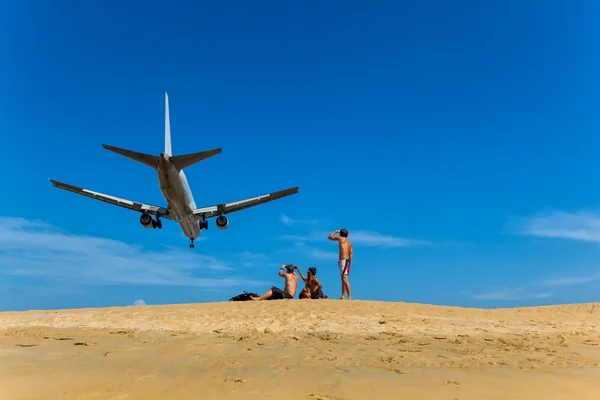 Men sit on the beach and look at them on a plane flying over