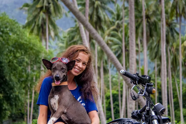 Woman sitting on the bike and holding a dog