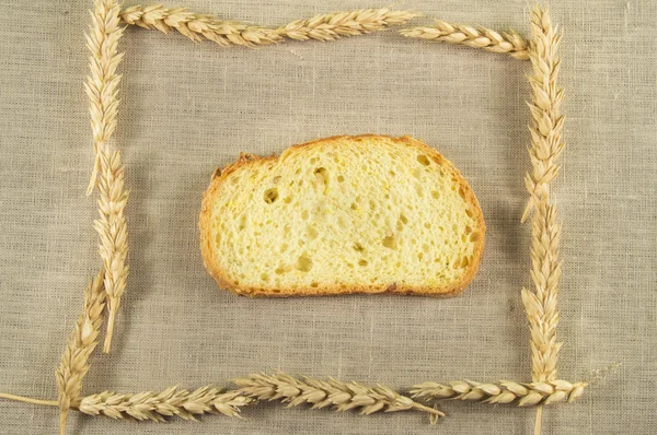 Frame of wheat ears with bread on a linen cloth