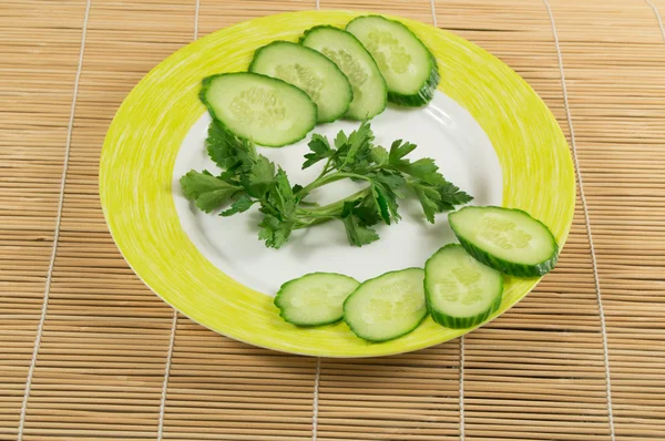 Sliced cucumbers with a sprig of parsley on the plate. The concept of weight loss and diet. Bamboo napkin