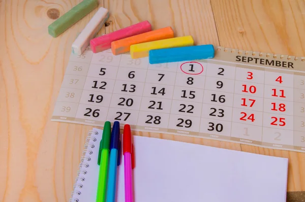 Back to school, calendar, colored chalk on wooden background