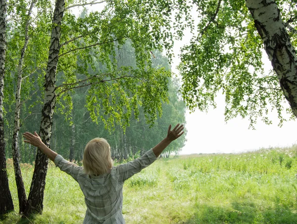 Woman near trees raised their hands. The concept of ecology and nature protection