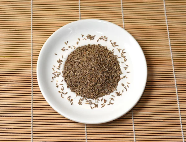 Spices in a white plate on bamboo Mat, top view