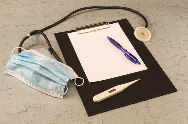 Table doctor, thermometer, stethoscope, mask, ballpoint pen, tablet for writing