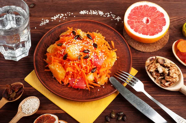 Concept diet food. Light salad with carrot, orange and grapefruit. Next to dried fruits and nuts, which are used in the preparation of a balanced diet. Vegetarian healthy food.