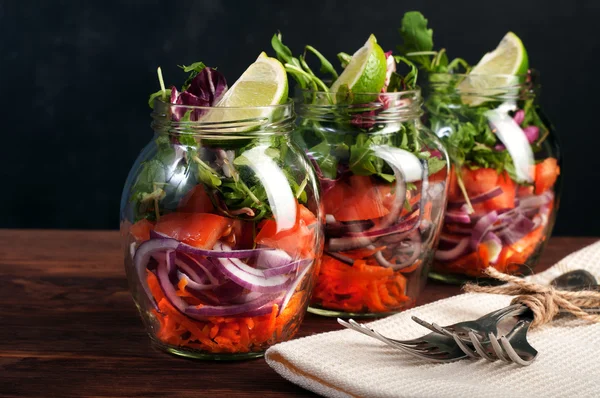 The concept of a healthy diet. Light salad of arugula, tomato, purple onion and lime, which you can take with you to work in a glass jar. Useful and tasty take away food.