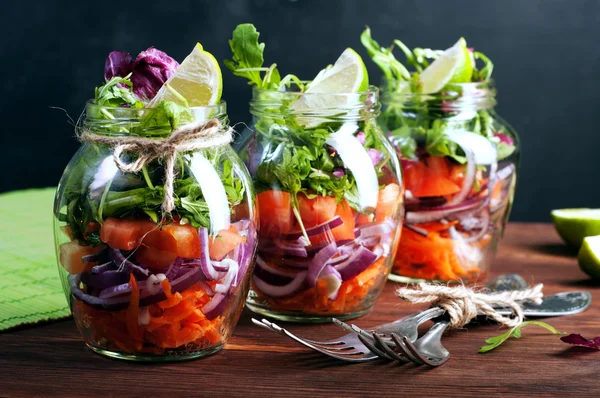 The concept of a healthy diet. Light salad of arugula, tomato, purple onion and lime, which you can take with you to work in a glass jar. Useful and tasty take away food.