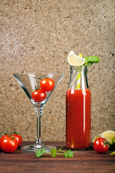 Tomato juice in a bottle on a wooden board. Brown background. Vegetarian concept. Non-alcoholic cocktail of tomato juice