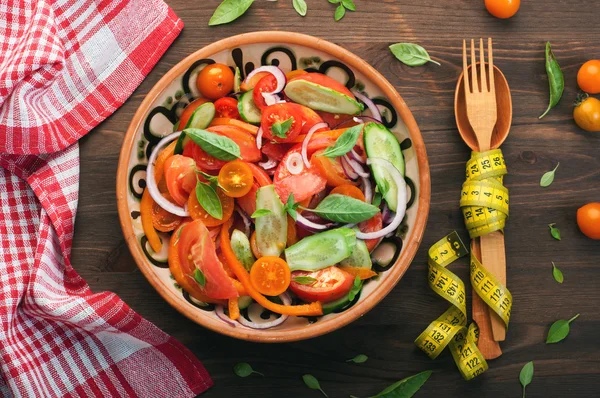 Plate of dietary vegetable salad of tomatoes, cucumbers, peppers, purple onion and basil. Concept diet food. Low-fat vegan diet